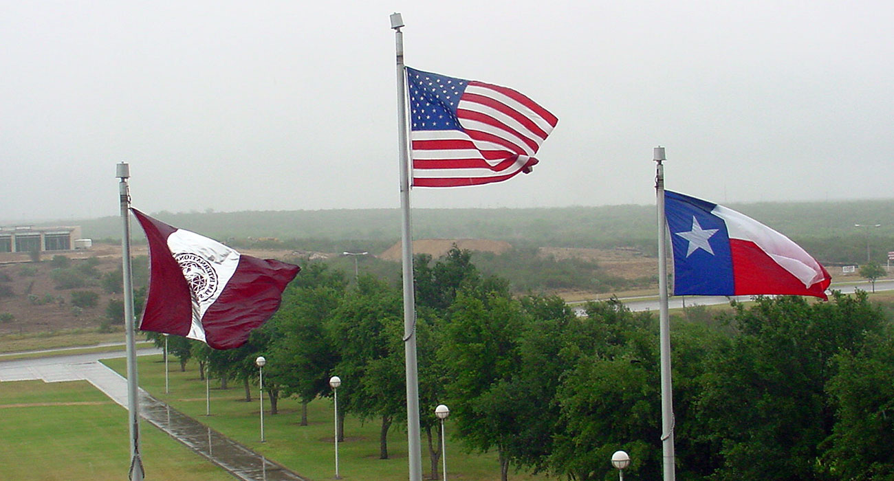 TAMIU flags on a raing day