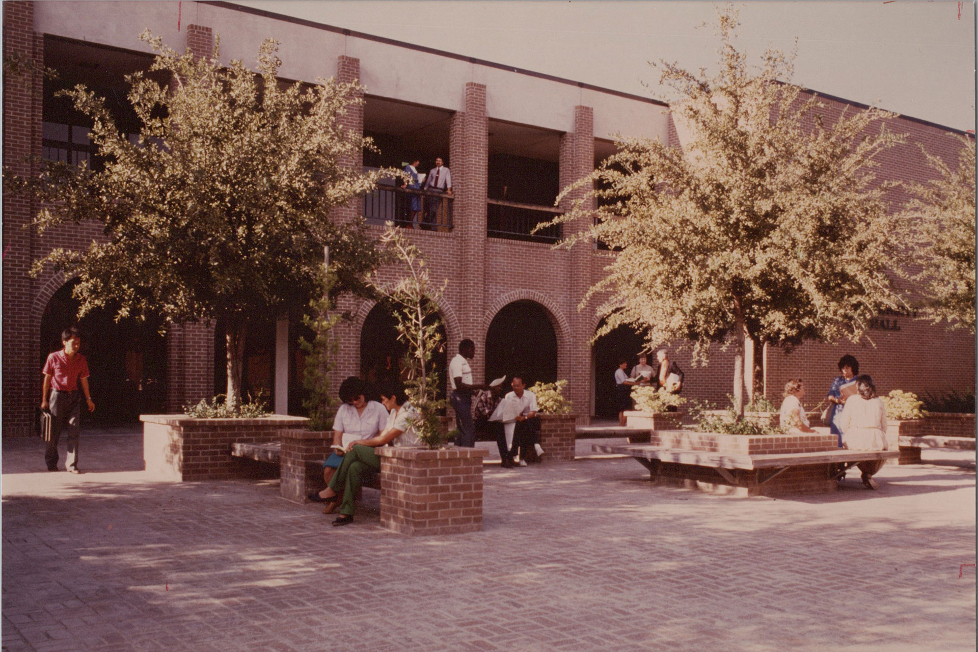 Students life is vibrant around the new University Hall. In the paved courtyard, students are studying, conversing with friends, and making their way to classes.