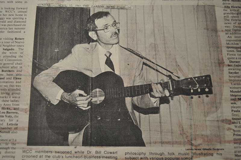 Dr. Billy Cowart plays his acoustic guitar in a light suit.