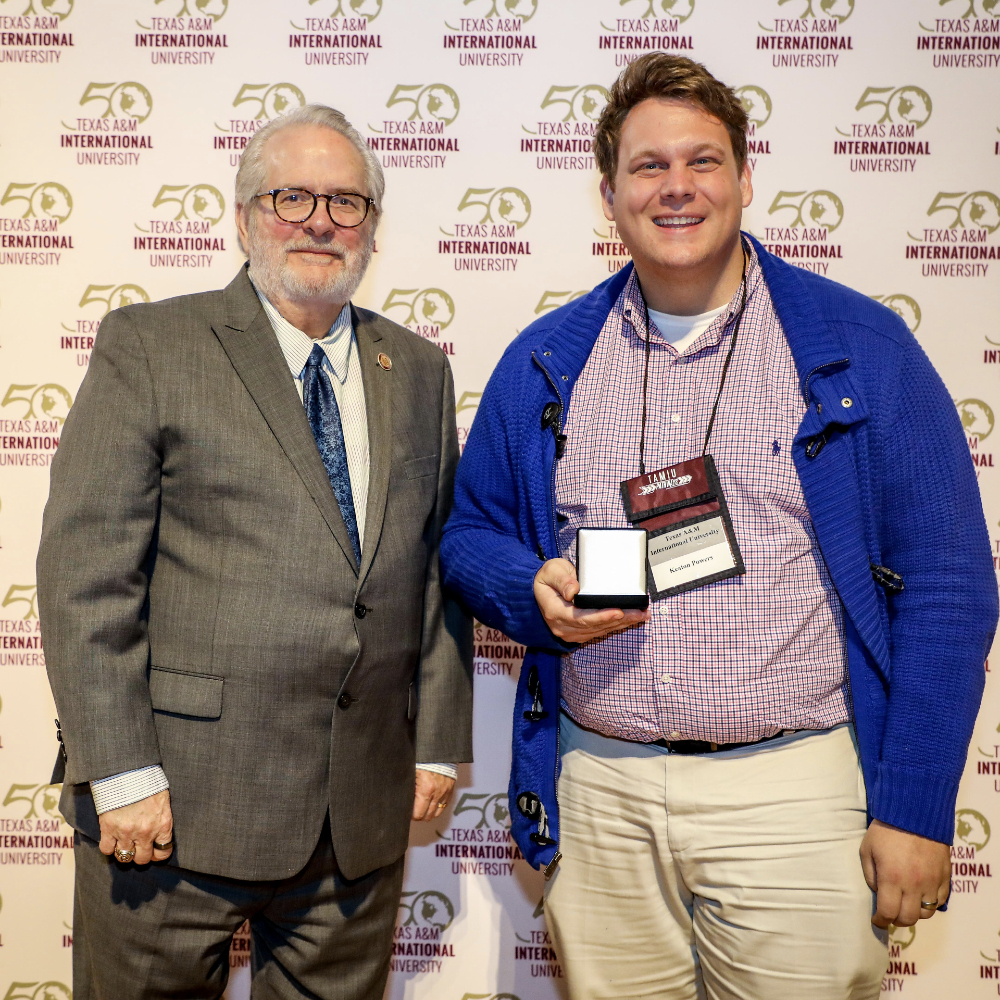 Dr. Mitchell, left, and Keaton Powers, right, smiling for the camera. Powers is holding his first place award.