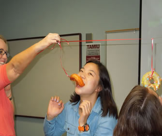 ESL student playing Sticky Face game, eating a doughnut