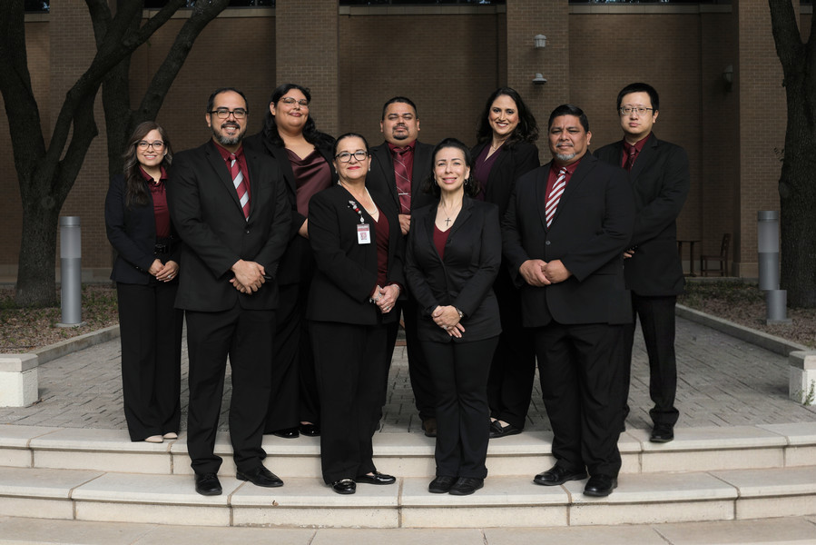 A group photo of a team standing and sitting together in front of a building.