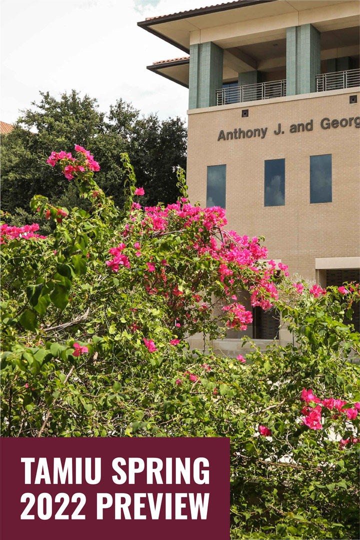 Pink flowers and green bushes with a TAMIU building in the background