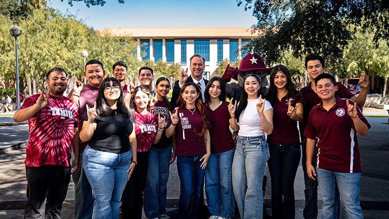 Dr. Christopher Maynard with students in front of the TAMIU Fountain