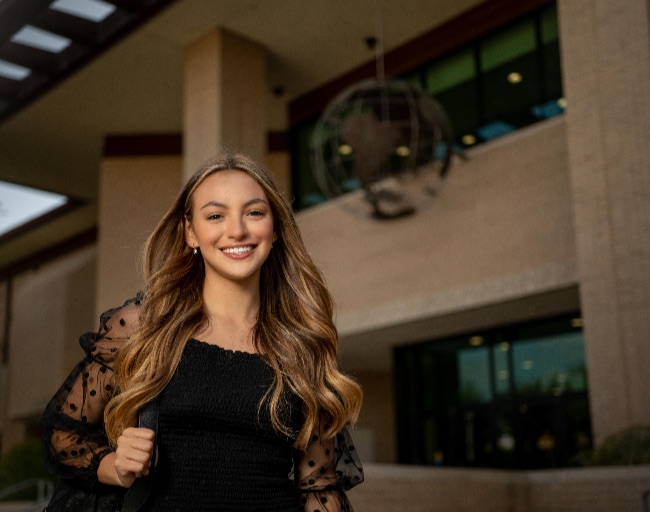 Student smiling in front of building