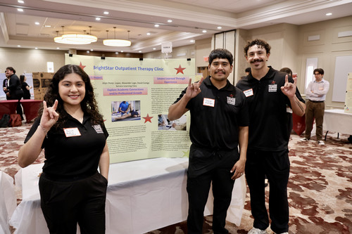 Group of smiling students in front of expo poster