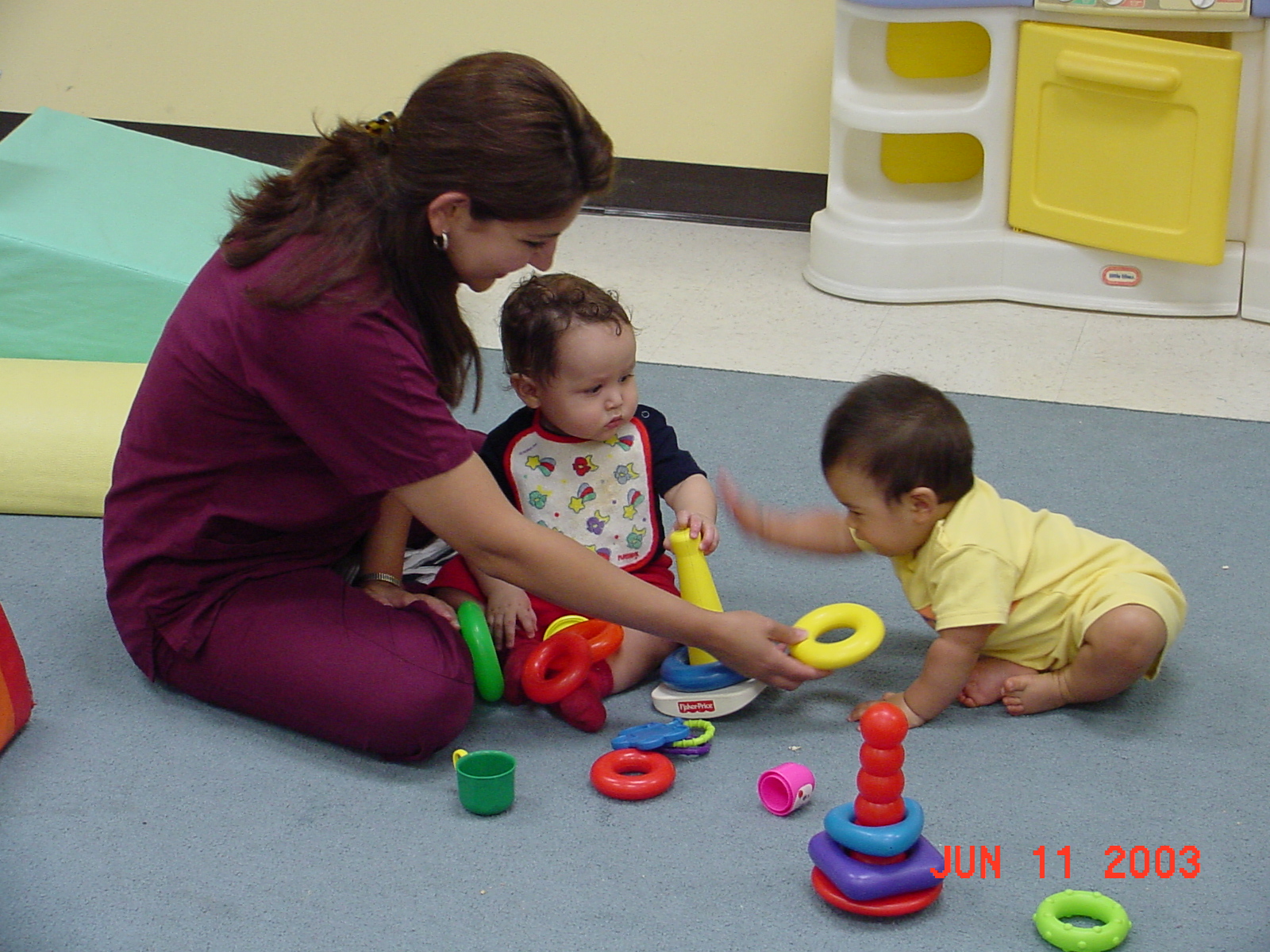 Child care worker playing with two infants. 