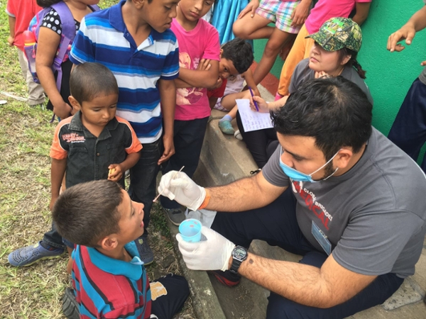 TAMIU Global Medical Brigade student conducting mouth swap for Honduran boy.