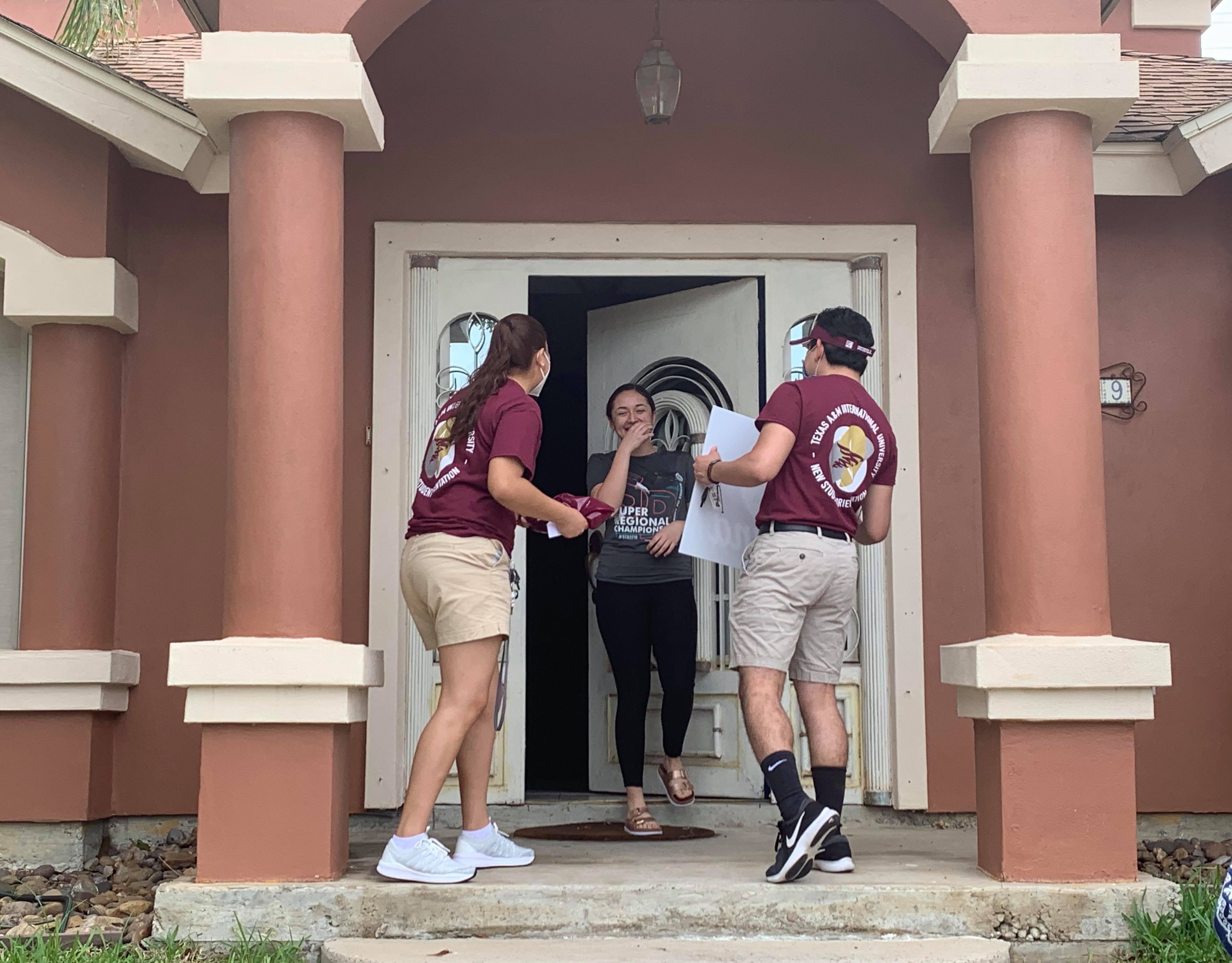 Texas A&M International University freshman student Maria Espericueta (center) was in for a surprise after New Student Orientation Leaders Yamile Vasquez (left) and Daniel Perez (right) brought a welcome packet and lawn sign to her home.