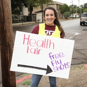 student holding health fair sign