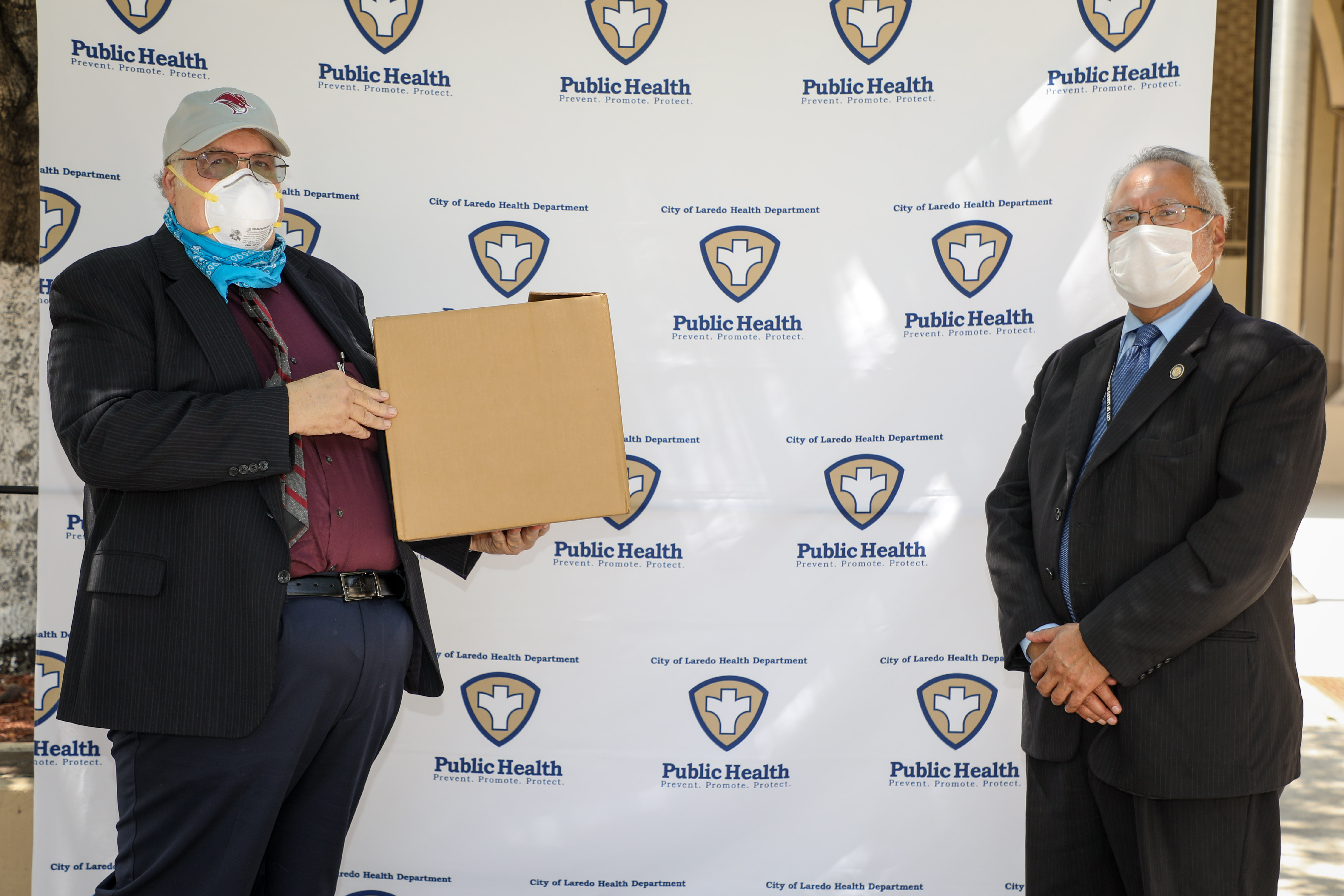 TAMIU president Dr. Pablo Arenaz presenting Laredo Health Department Director Dr. Hector González with 110 COVID-19 sampling kits