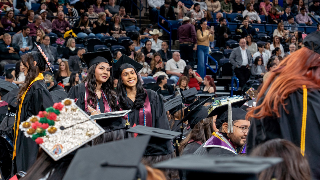 TAMIU graduate smile, stand together