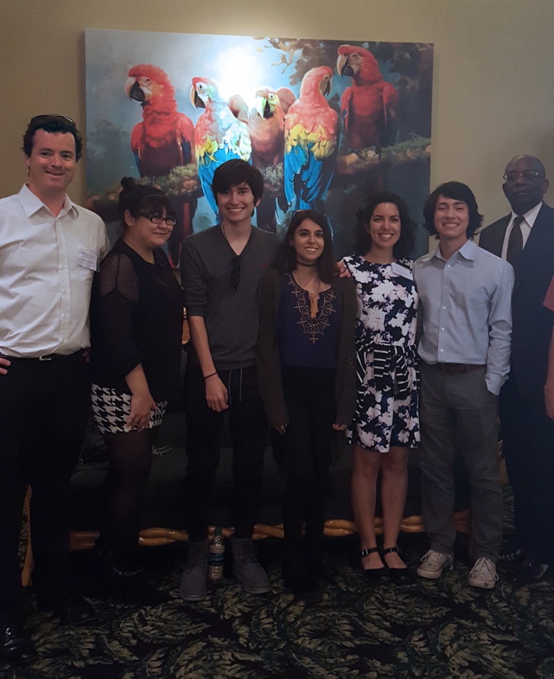 Jonathan Murphy and students in front of a painting of parrots