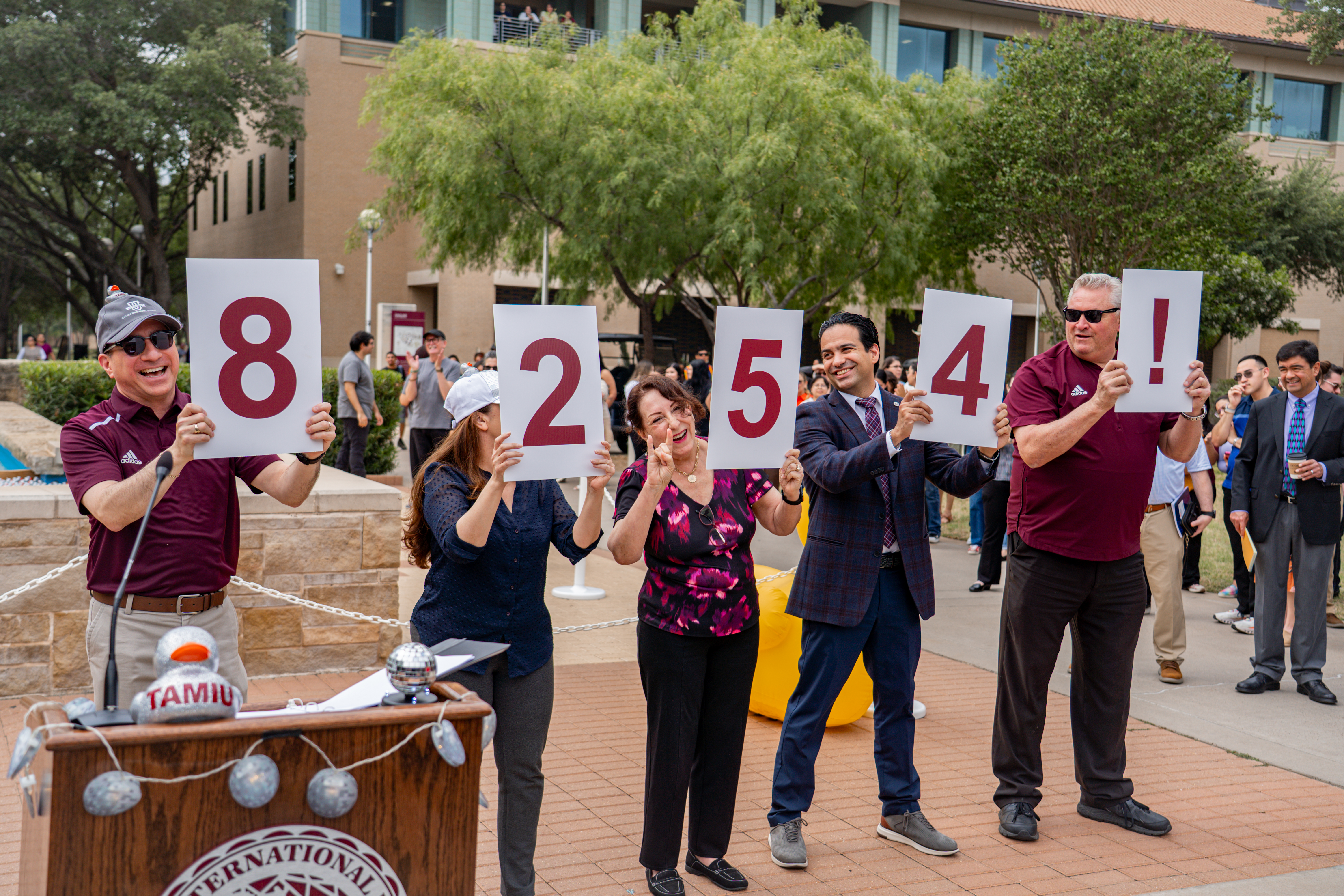 University administration stand and hold up the enrollment count numbers