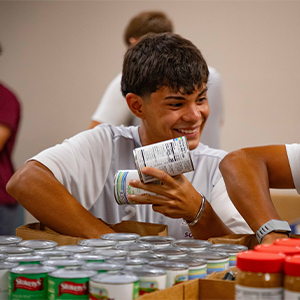 Student Smilling with Can of Food