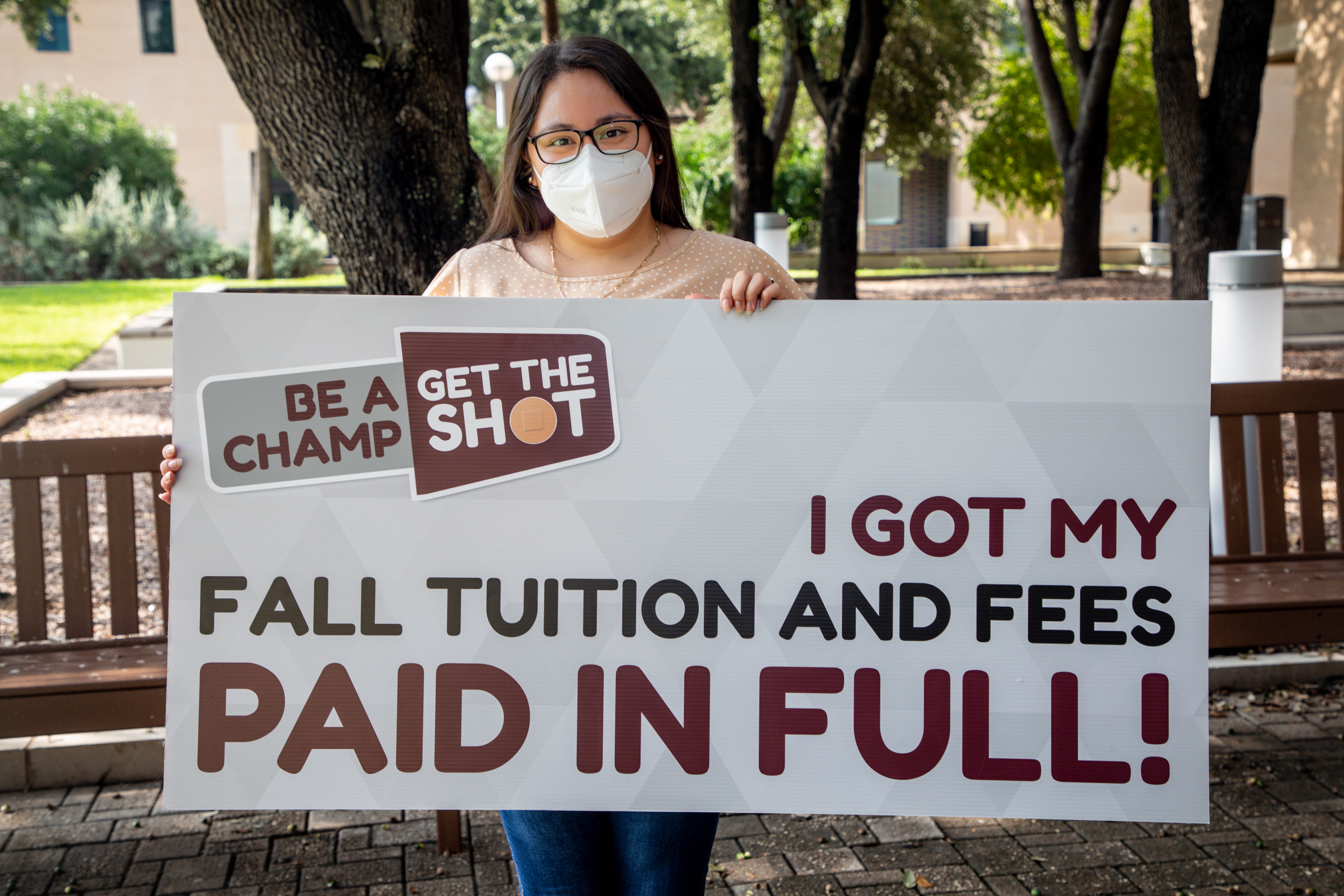First Be A Champ grand prize winner holding a large sign saying "I got my Fall tuition and fees paid in full!"