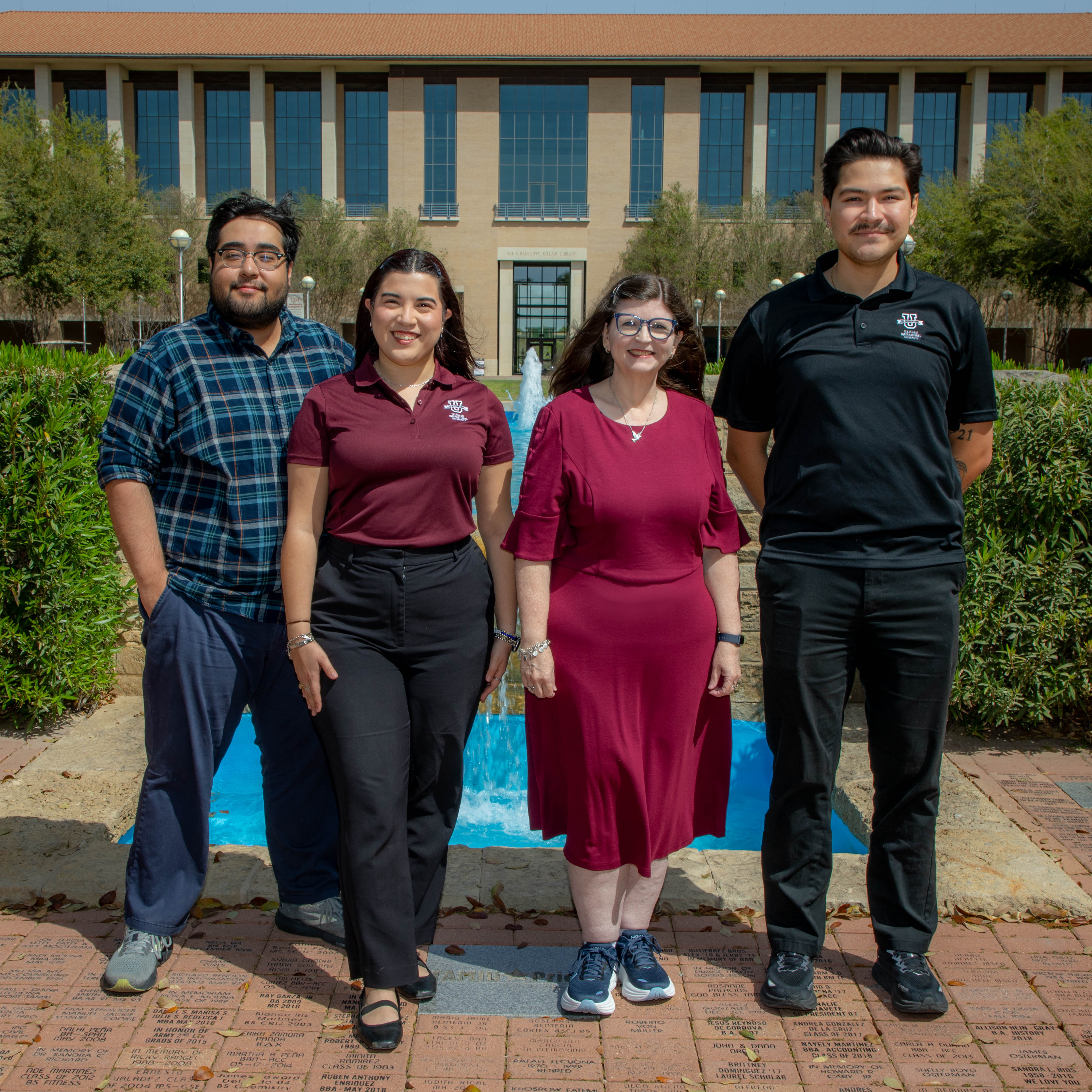 A TAMIU faculty member, alum and a current graduate student stand in front of the Acequia Fountain
