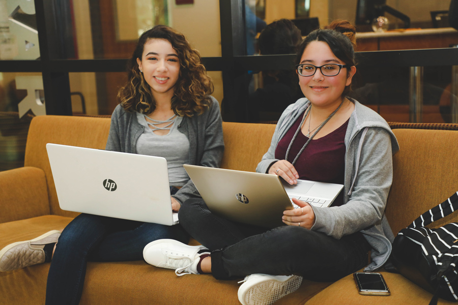 two students holding laptops