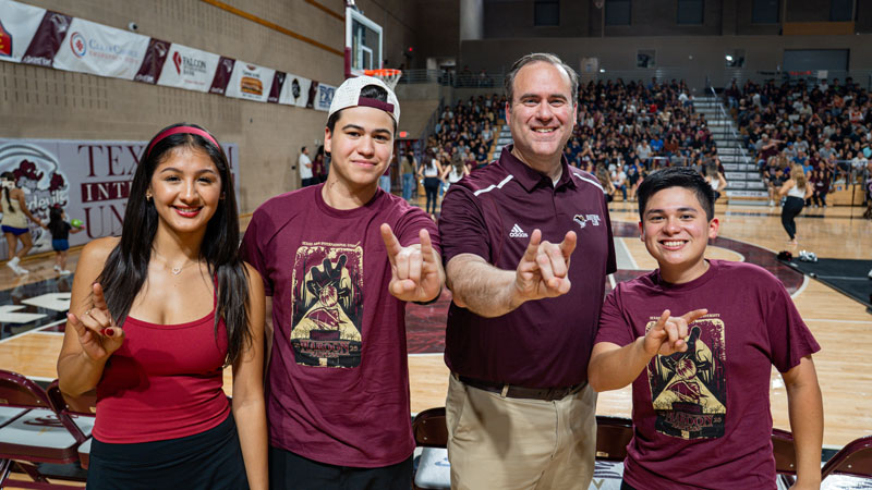Dr. Maynard with students making Dustdevil handsign during Maroon Madness 2025