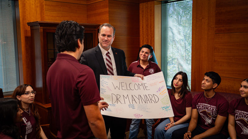 Students presenting Dr. Maynard with a signed poster that reads ‘Welcome Dr. Maynard’