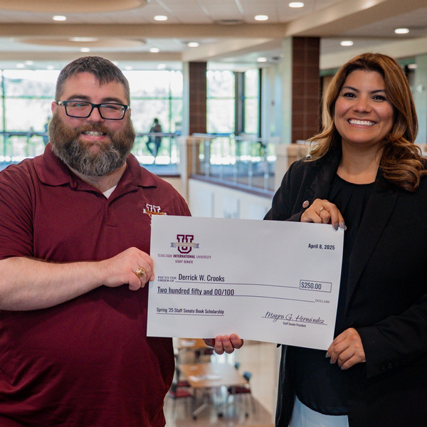 Christine Rojas given a check by Staff Senate President Mayra Hernandez