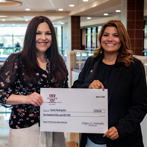 Isabel de Leon given a check by Staff Senate President Mayra Hernandez