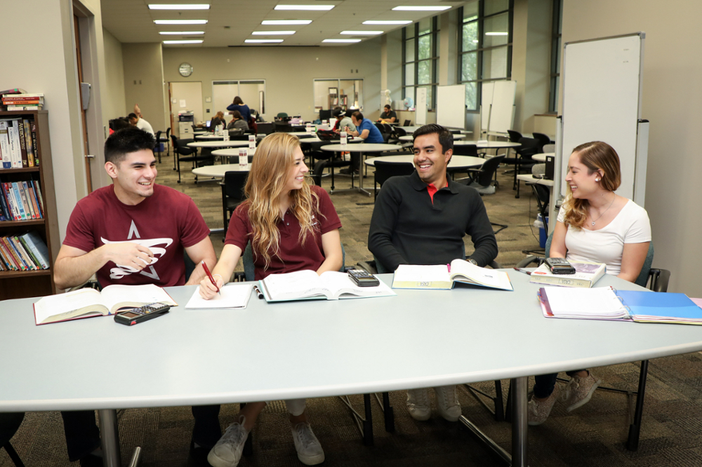 Four students in tutoring session talking and smiling