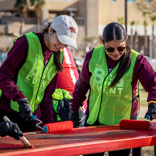 Students volunteers painting a bench 